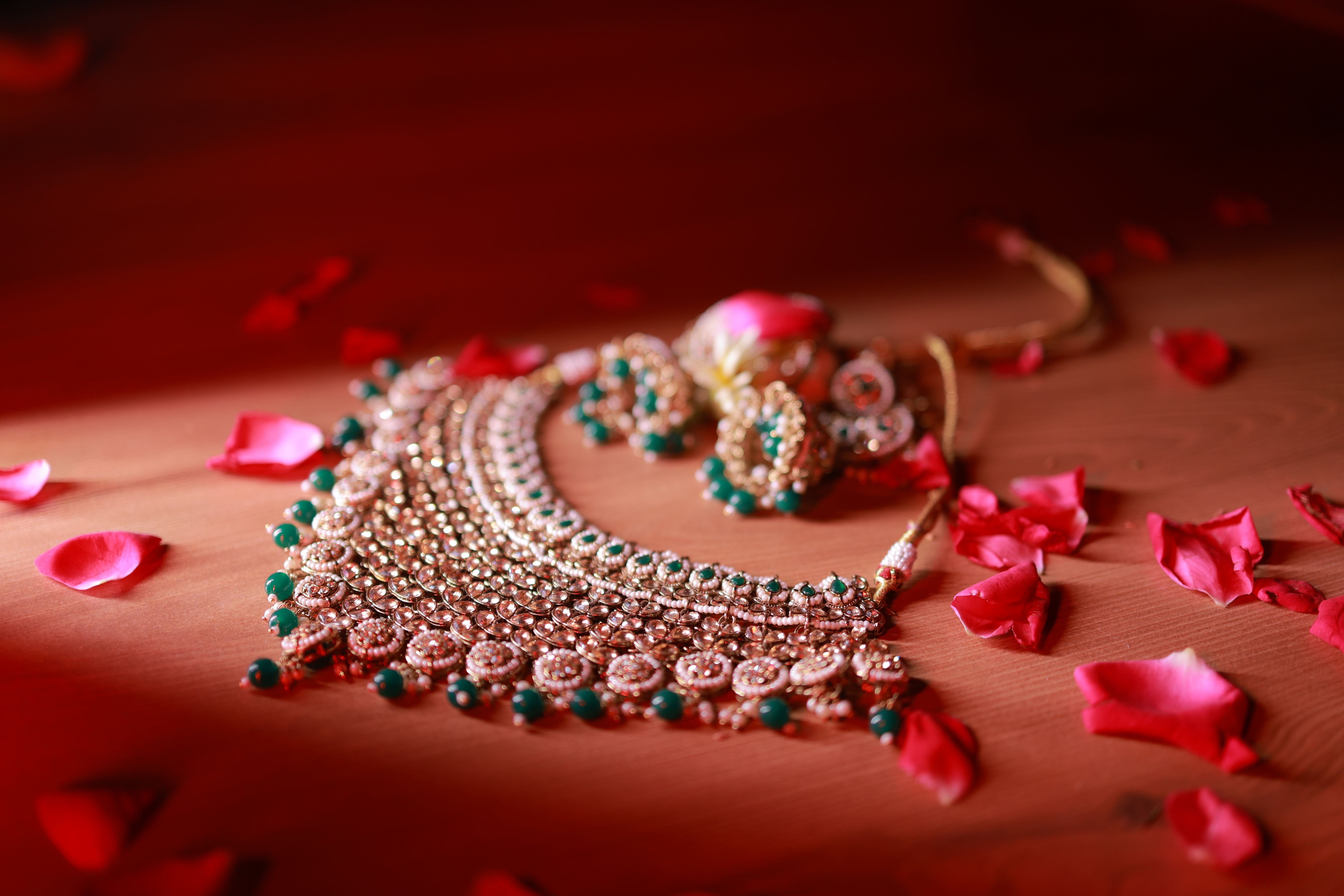 Close-up still life of an ornate Indian gold necklace with green stone accents