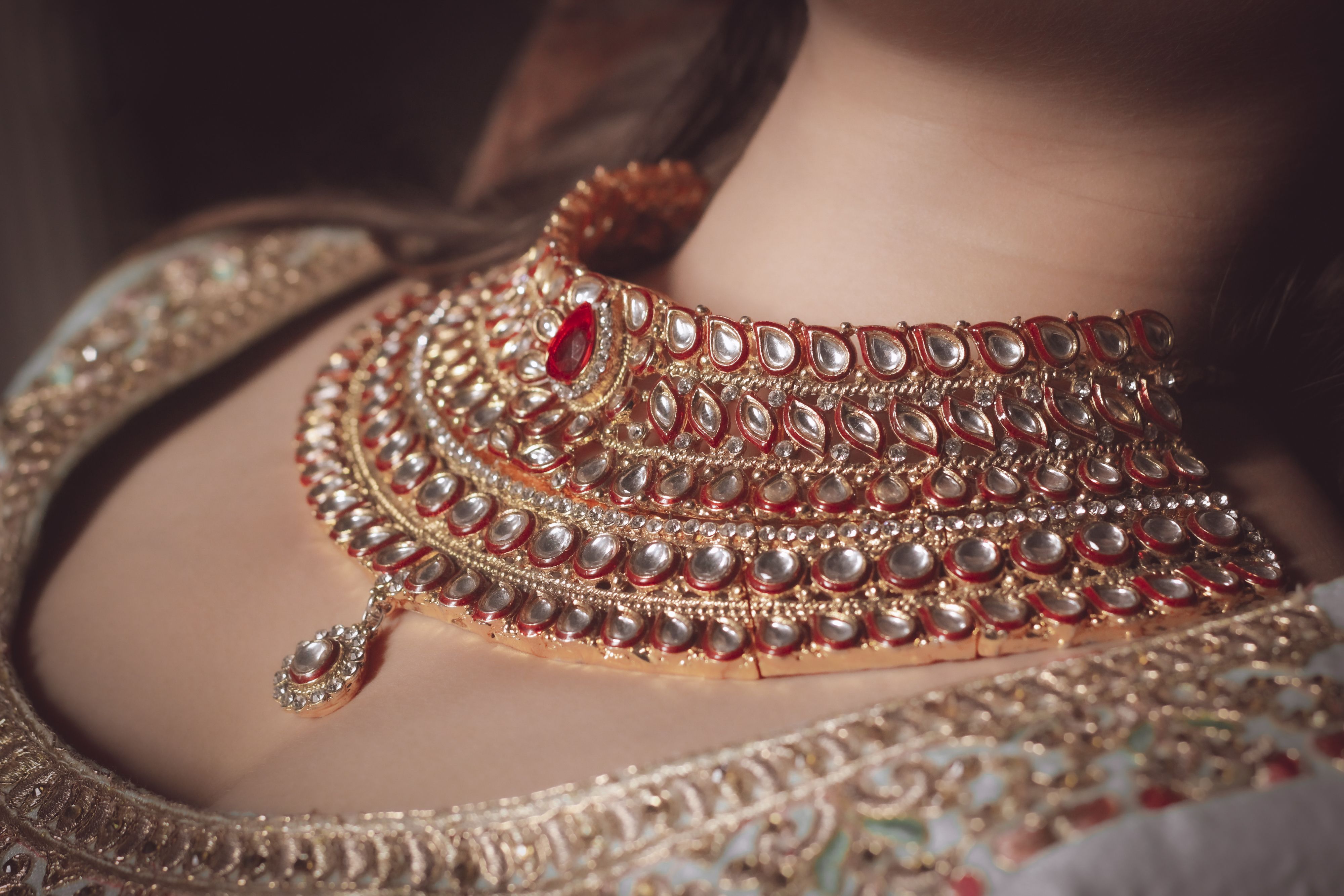 Bride adorned in an intricate traditional Indian gold necklace, haram, and ceremonial attire